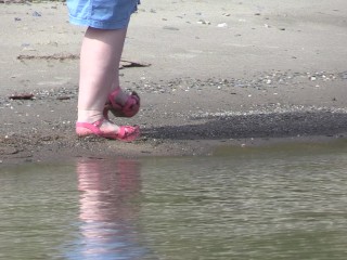 On high heels and bare feet on the_sand, plump legs walk along the_shore.