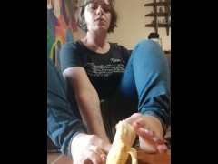 Peels a banana with her toes and takes a big bite