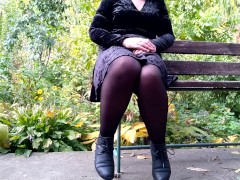 Peeing with legs spread wide on a bench in an autumn park