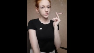 Smoke A Redhead Girl Smokes A Cigarette While Her Hair Is Pulled Back Into A Bun