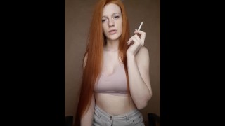 A Young Woman With Red Hair And Long Hair Smokes A Cigarette With A Brown Filter