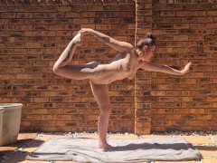Tattooed brunette doing stretches outside in the sun while being completely naked