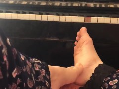 Чудесные ступни девушки на фоне пианино