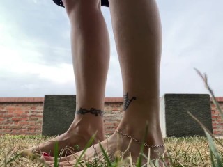 Slow motion milf barefoot in grass, wrinkled soles and red toes