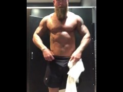 Fit tattooed man strips in gym locker room