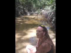Cute long hair girl on her knees looking for shells to collect in popular spring creek