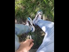 Young guy in sneakers and blue jeans smoke in the forest